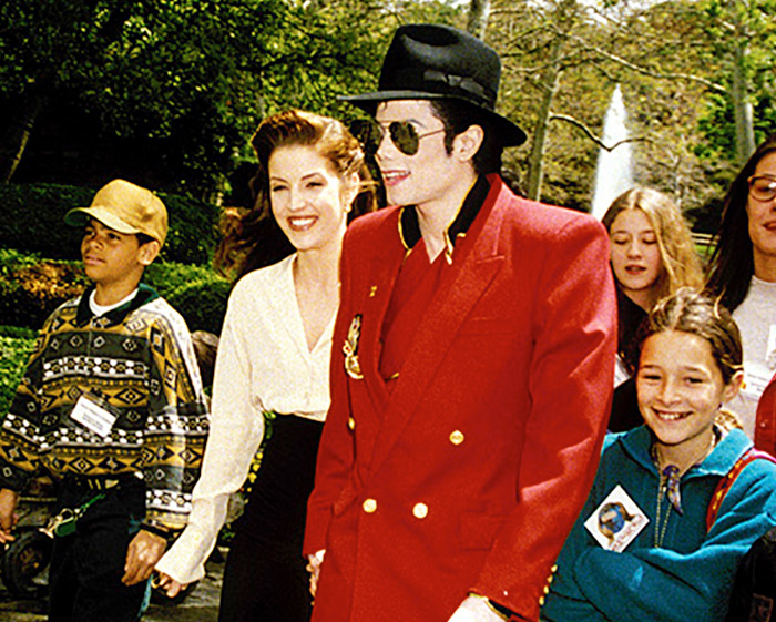 Michael Jackson and Lisa Marie Presley walking together in public with a crowd.
