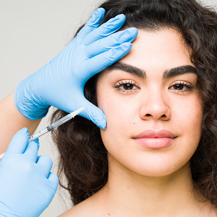A woman receiving a facial injection, depicting a common plastic surgery trend. A woman receiving a facial injection, depicting a common plastic surgery trend.
