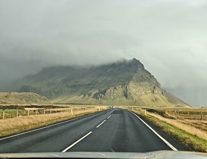Mountain view from a highway with overcast sky and green fields
