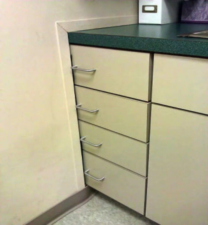 A kitchen renovation fiasco with drawers installed in a corner, unable to open due to overlapping trim.