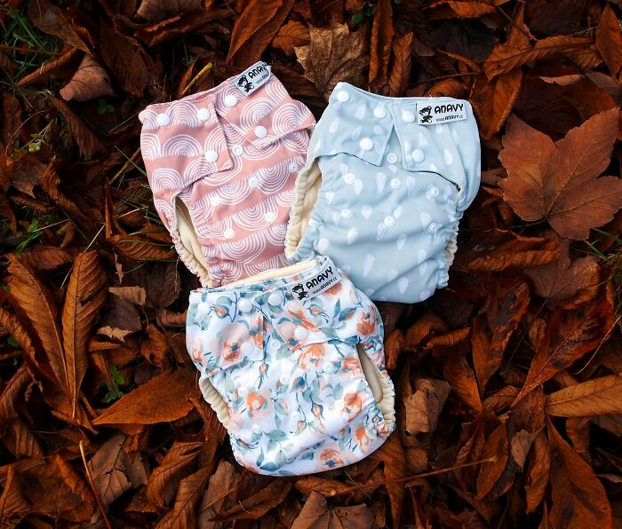 Three patterned cloth diapers laid on autumn leaves