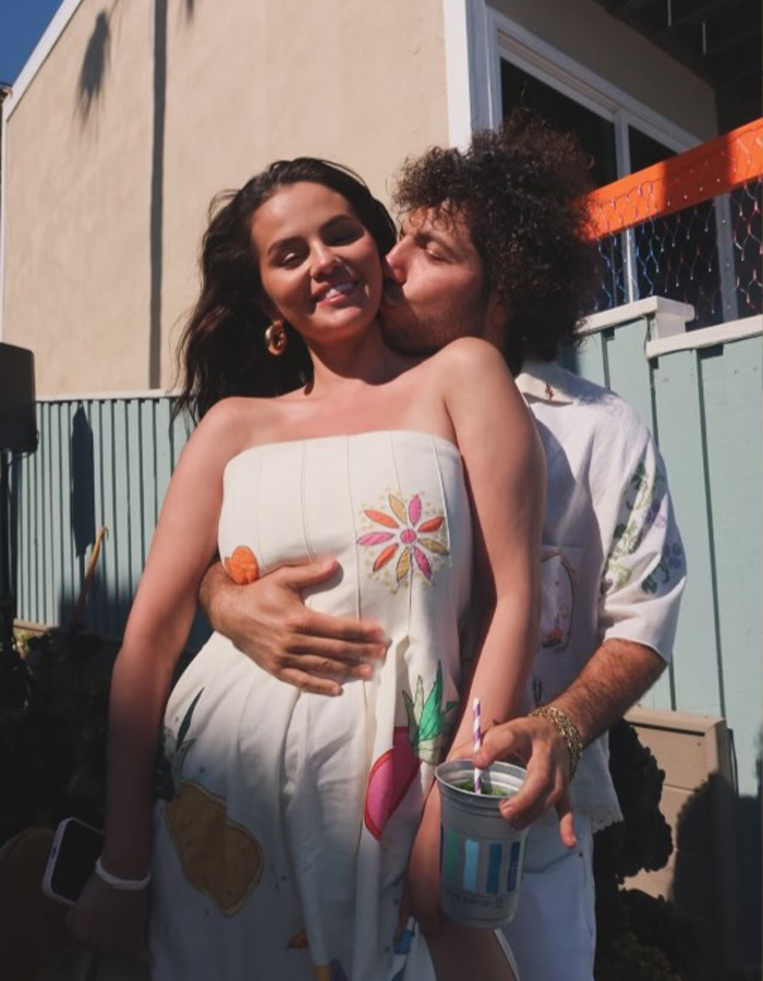 Benny Blanco kisses Selena Gomez on the cheek as she smiles outdoors in a floral dress Benny Blanco kisses Selena Gomez on the cheek as she smiles outdoors in a floral dress