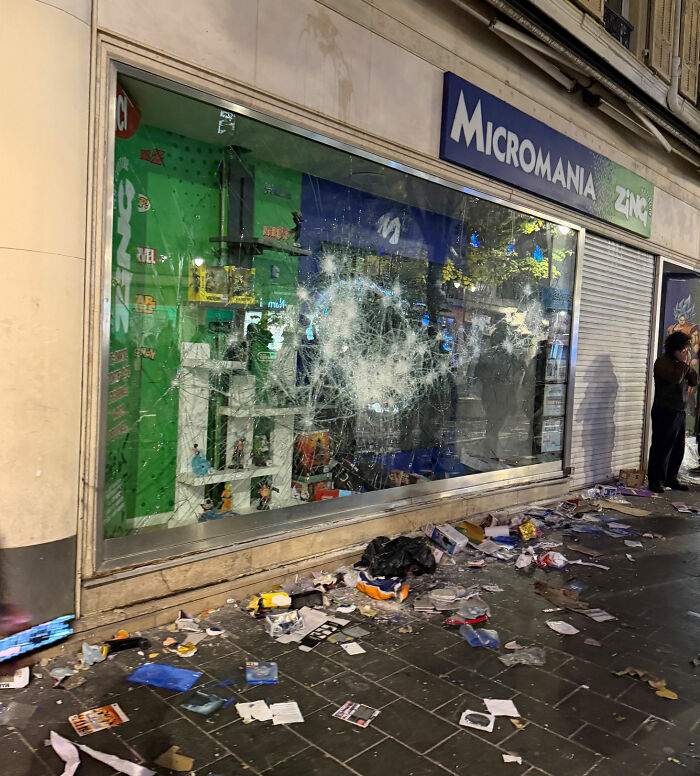 Storefront with broken glass and debris during France riots