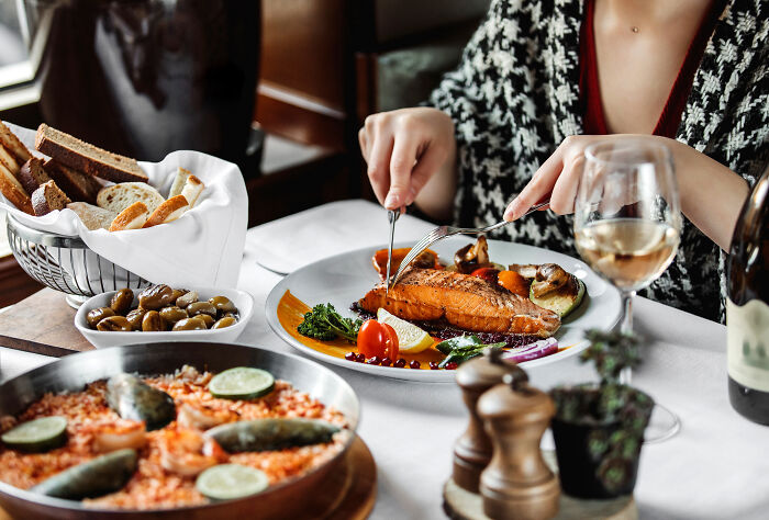 A person dining on gourmet salmon, showing the quality behind the scenes at companies people trust.