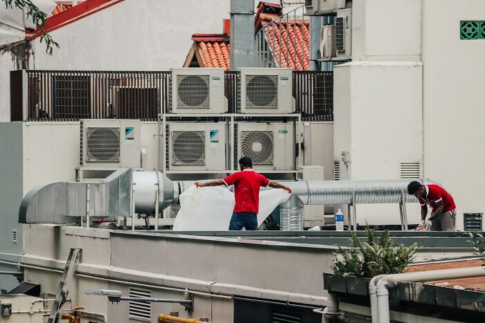 Workers installing ventilation systems on a rooftop, highlighting Hollywood movie myths of ventilation shafts.