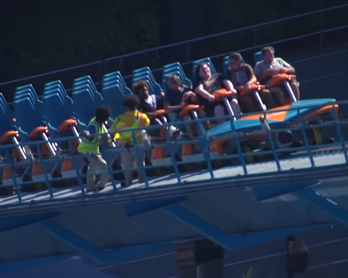 Park attendants inspecting riders on a Six Flags roller coaster track. Park attendants inspecting riders on a Six Flags roller coaster track.