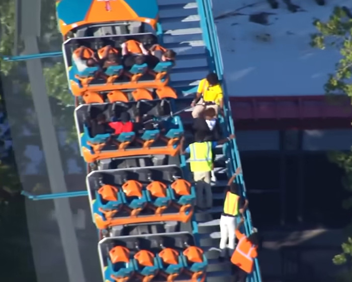 Top-down view of employees assisting passengers on a Six Flags roller coaster. Top-down view of employees assisting passengers on a Six Flags roller coaster.