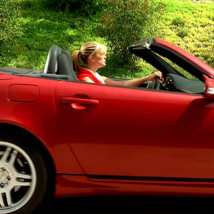 A blonde woman driving a red sports car, reminding millennials of the Stacy's Mom music video. A blonde woman driving a red sports car, reminding millennials of the Stacy's Mom music video.