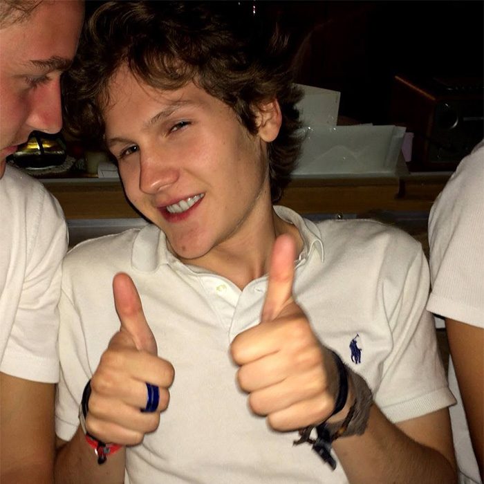 A smiling video game creator and influencer giving two thumbs up while wearing a white polo shirt.