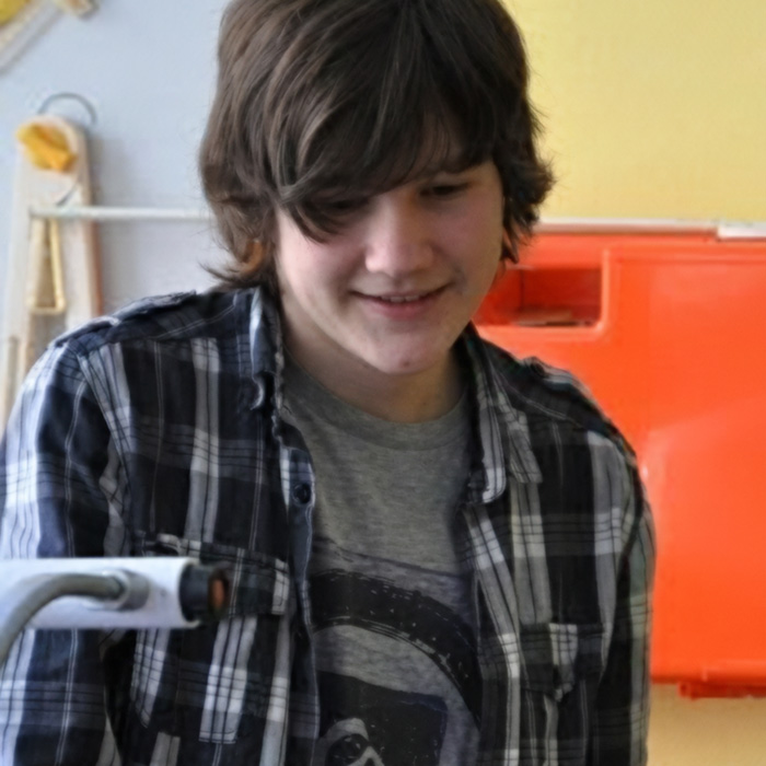Portrait of video game creator Manuel Joshua B. wearing a plaid shirt, smiling indoors.