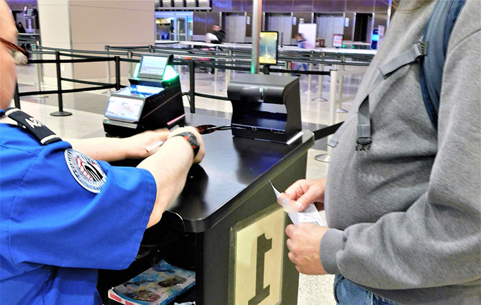 TSA officer checking traveler boarding pass at airport security gate