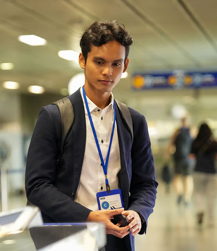 Young male traveler looking down at his phone while waiting at a TSA security checkpoint