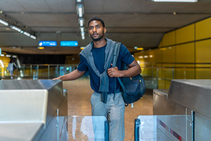 A young male traveler passing through transit turnstiles, representing travelers stopped by TSA