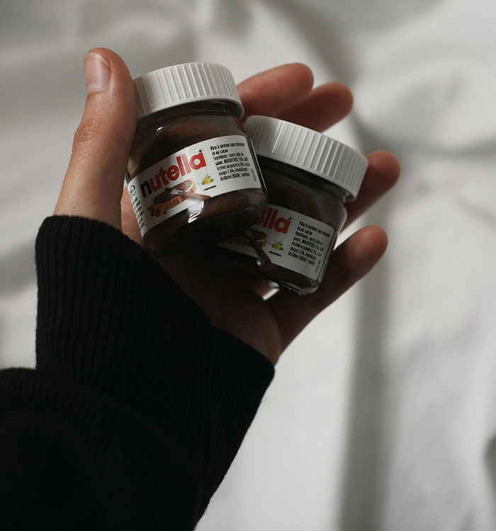 Hand holding two miniature Nutella jars representing items confiscated by TSA