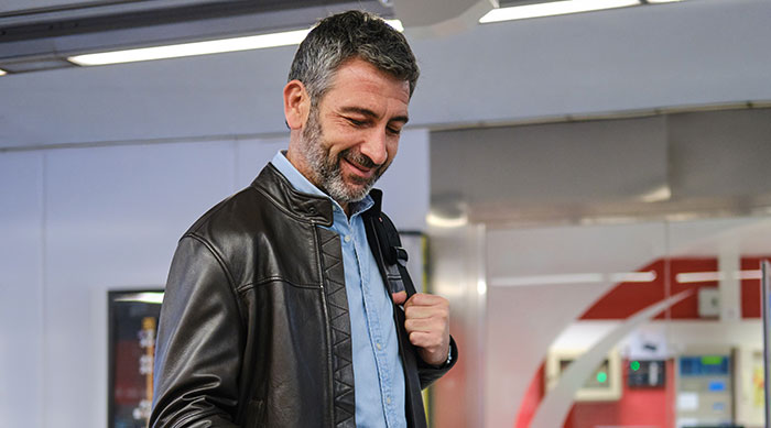 A middle-aged male traveler smiles in transit, referencing travelers stopped by TSA