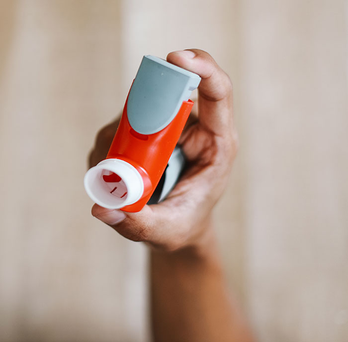 A hand holding an inhaler, demonstrating items travelers got stopped by TSA for having in carry-on bags