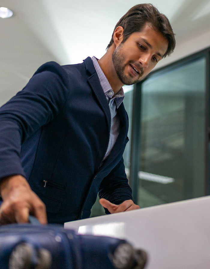 A male traveler adjusting his suitcase, reminding of travelers stopped by TSA