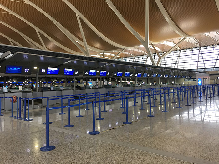 Empty airport check-in counters with blue queue ropes, representing travelers stopped by TSA.