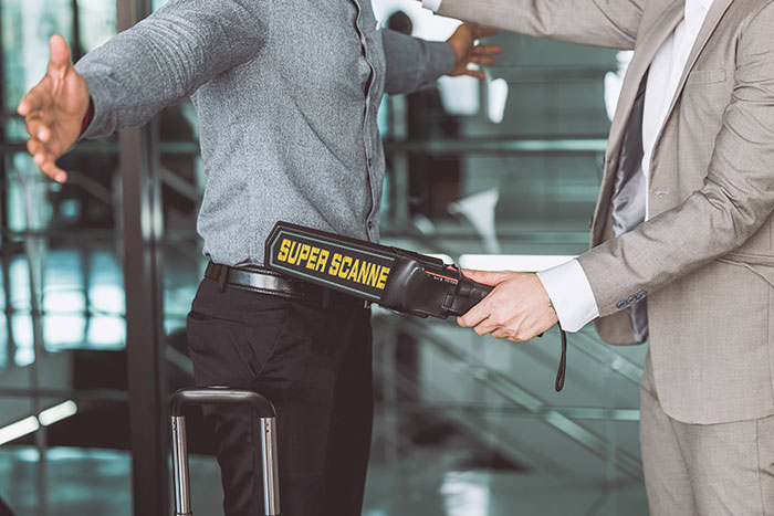 Traveler scanned with hand metal detector at airport checkpoint