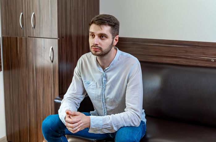 A man sitting quietly on a couch, representing the realization of living with guys.