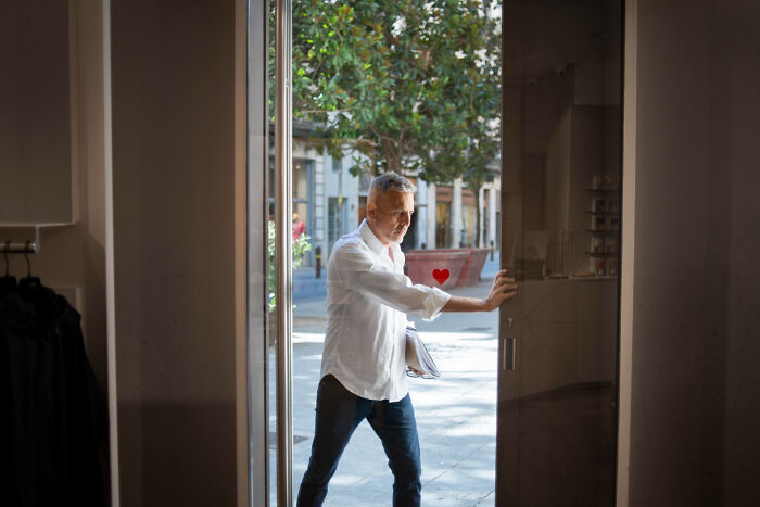 An older man opening a glass door from the outside, showing a detail about living with guys.