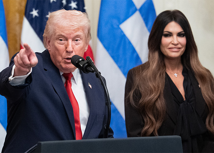 Donald Trump speaking at a podium next to a woman with long hair during discussion of Susan Dell transformation.