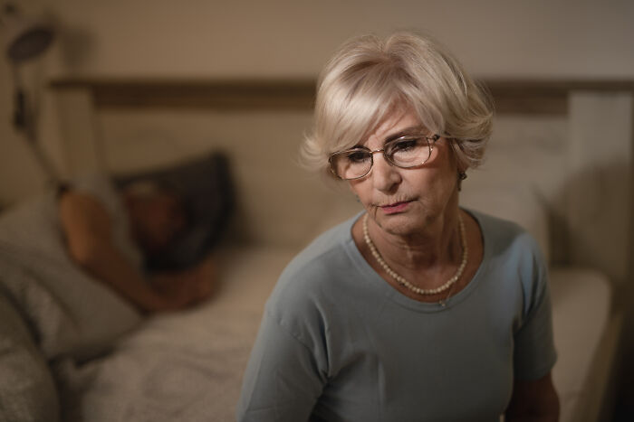 Worried senior woman sitting on a bed representing being disowned by their families