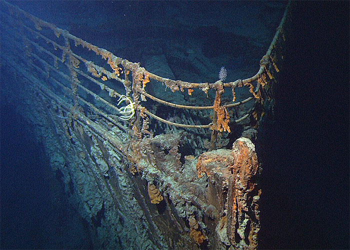 Rust-covered bow railing of the Titanic shipwreck resting deep on the ocean floor. Rust-covered bow railing of the Titanic shipwreck resting deep on the ocean floor.