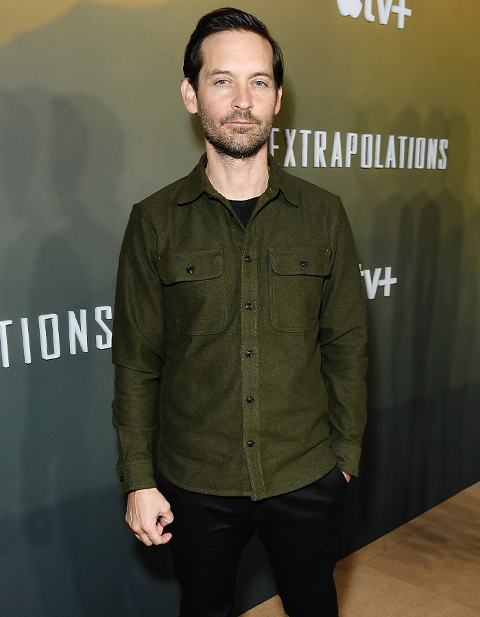Tobey Maguire at age 51 posing on a red carpet in a green shirt Tobey Maguire at age 51 posing on a red carpet in a green shirt