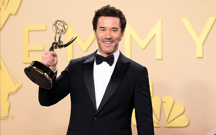 Tom Pelphrey holding an award, star of the controversial Netflix miniseries.