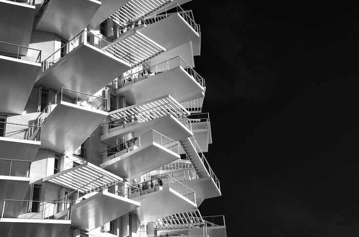 Angled view of a modern white building facade highlighting unique buildings and spaces