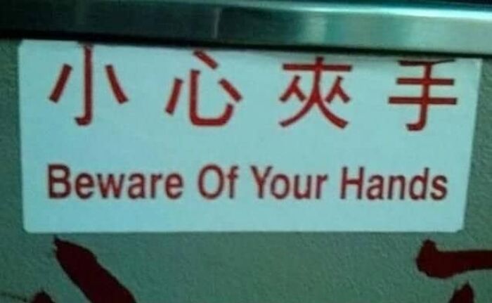 A warning sign showing translation fails stating beware of your hands in red lettering.