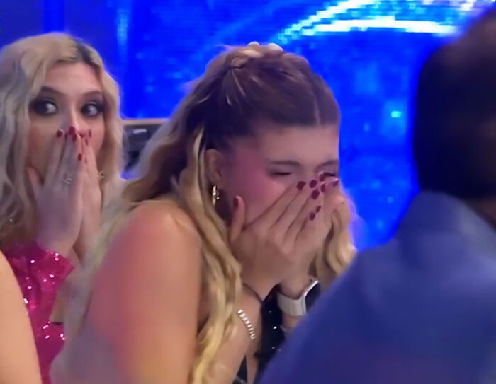 Shocked woman covering her face after TV show host kicks drone into model's face.