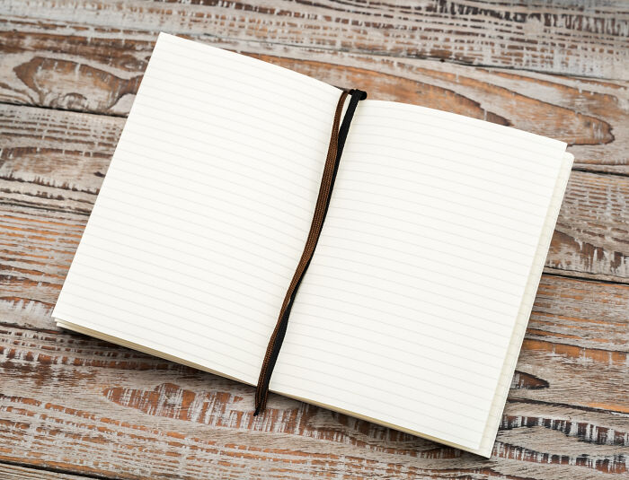 An open blank notebook lying on a rustic wooden table, ready for quick-fire jokes.