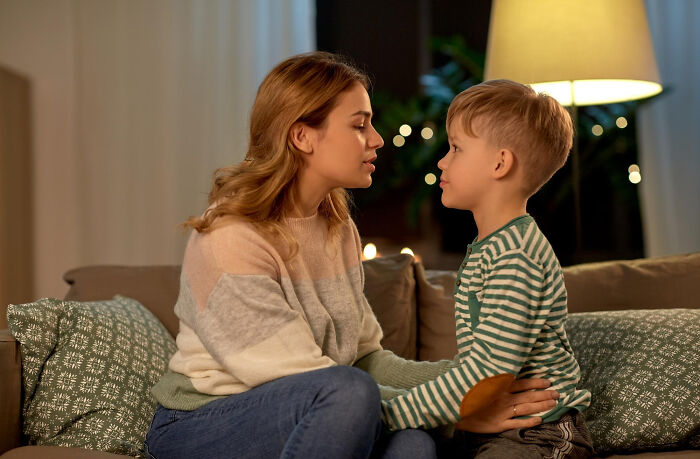 A mother talking softly to her young son on a couch as part of quick-fire jokes