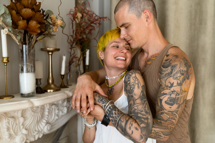 A heavily tattooed couple hugging indoors, illustrating quick-fire jokes.