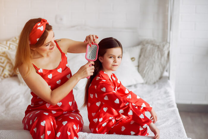 Mother brushing her daughter's hair in matching pajamas, sharing quick-fire jokes.