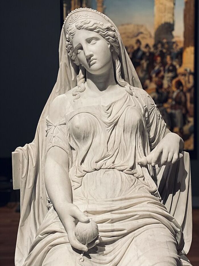 Classical white marble statue of a seated woman, representing timeless art and quick-fire jokes.