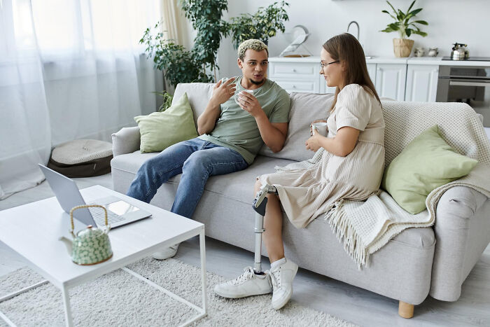 Couple sitting on a sofa chatting over coffee and telling quick-fire jokes.