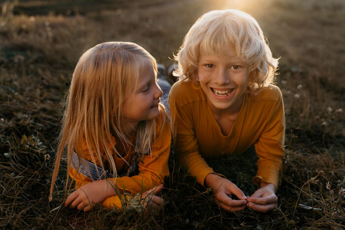 Two kids lying in the grass smiling and sharing quick-fire jokes.