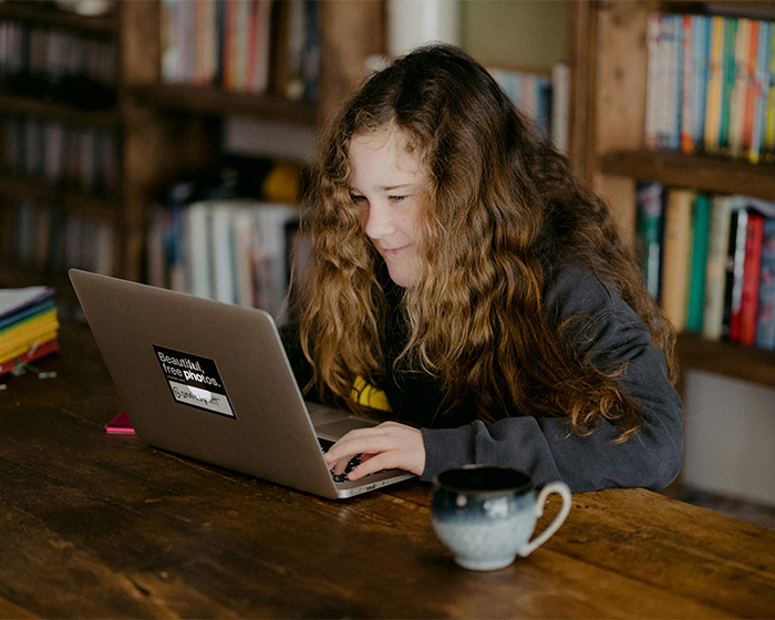 Young student typing on a laptop computer at home, working on homework.