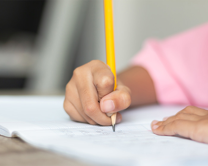 Close up of a student using a pencil to write, relating to UC Berkeley professor grading policies.