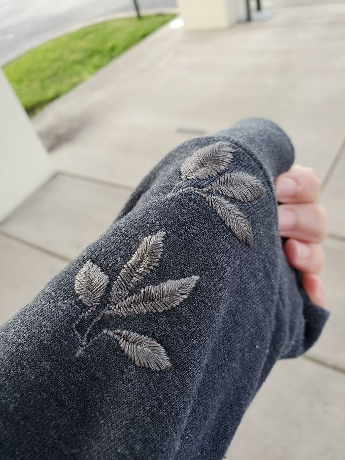 Delicate leaf embroidery repairing a grey sleeve, illustrating how creativity can save money.