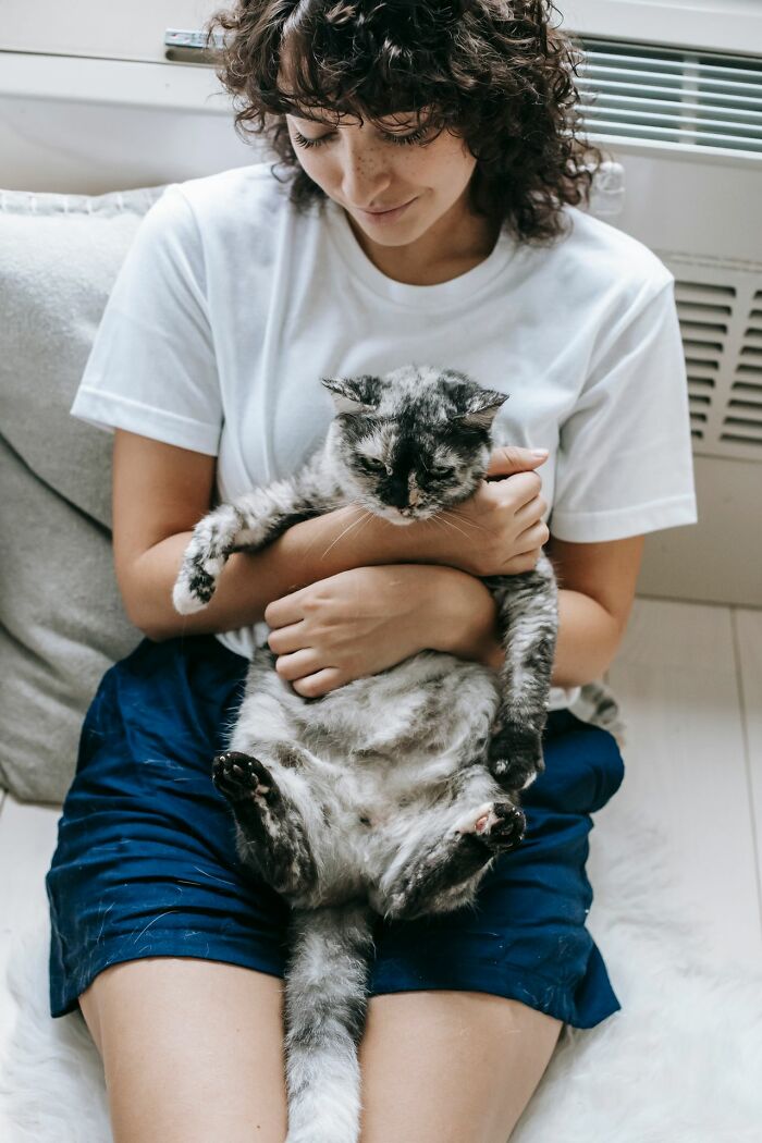 A woman holding a fluffy cat, representing true stories people rarely tell.