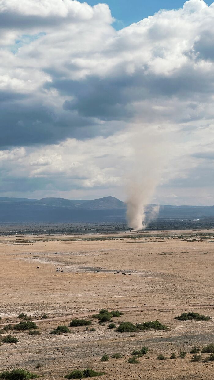 A large dust devil spinning in an open desert plain, like true stories of strange weather phenomena.