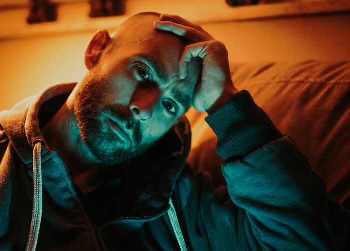 A thoughtful man resting his head on his hand while contemplating true stories.