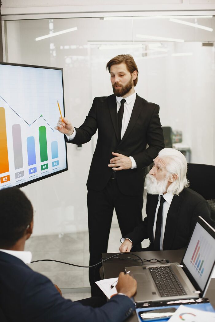 Man pointing at graphs during business presentation about true stories