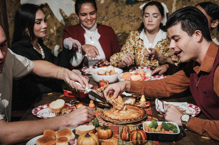 A group of diverse people enjoying a Thanksgiving meal and true stories together.