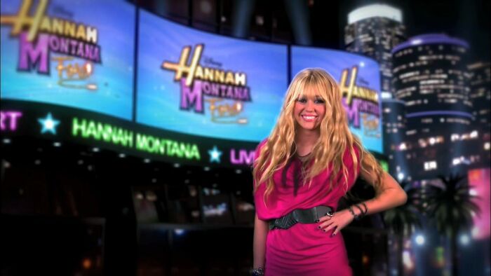 A woman in a pink dress in front of billboards, sharing true stories rarely believed.