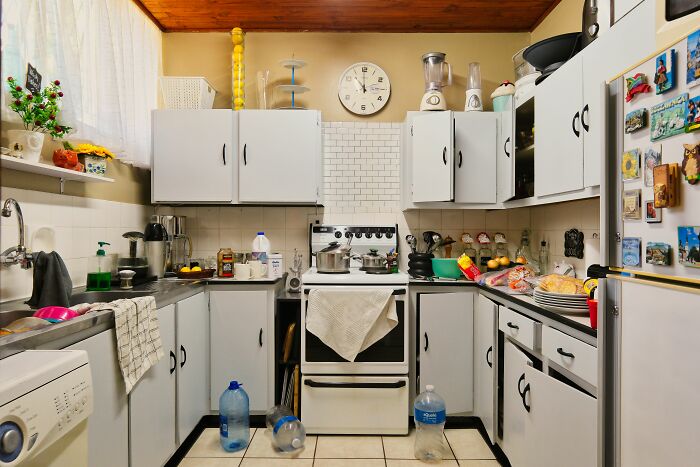 A cluttered kitchen featuring messy countertops, highlighting unethical life pro tips for organizing home space